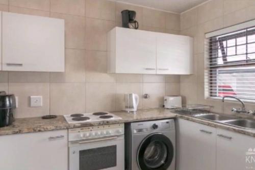 a kitchen with a stove and a washing machine at Waterfront Apartment in Knysna