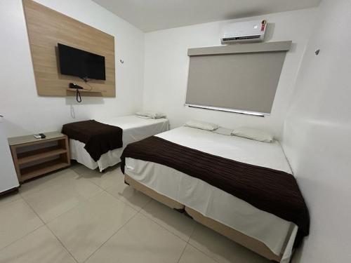 a room with two beds and a flat screen tv at Mais Hotel Express in São Luís