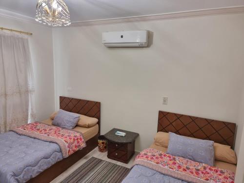 a bedroom with two beds and a couch and a chandelier at TBK1 apartment in Alrehab city for families only in Burg el-Ḥudûd