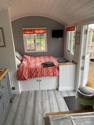 a small bedroom with a bed and a television at The Shepherd's Hut in Mixbury