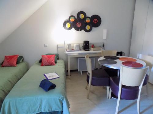 Cette chambre comprend deux lits et une table avec des disques sur le mur. dans l'établissement TITHOME 3 - Grand studio bus gare centre ville sanctuaire, à Lourdes