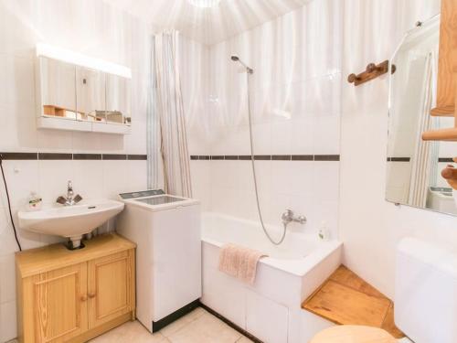 une salle de bain blanche avec un lavabo et une douche dans l'établissement Appartement cœur de village, à Samoëns