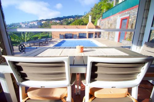 a table and two chairs on a balcony with a pool at Casa da Rainha Bungallow in Estreito da Calheta
