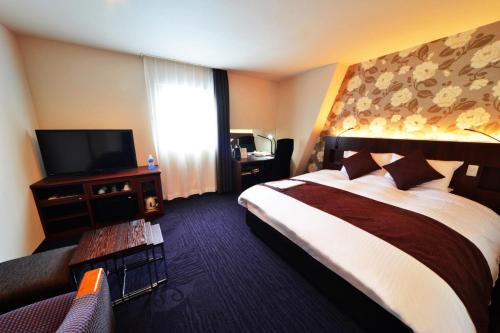 a hotel room with a bed and a flat screen tv at Kushiro Century Castle Hotel in Kushiro