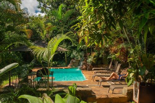 une personne assise dans une chaise à côté d'une piscine dans l'établissement Karibu Entebbe, à Entebbe