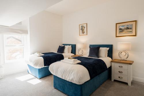 a bedroom with two beds and a window at Spacious & modern 2 bed flat in Hoylake - Opposite Royal Liverpool Golf Club in Hoylake