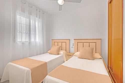 ガンディアにあるBitacoraの白い壁の客室で、ベッド2台、窓が備わります。
