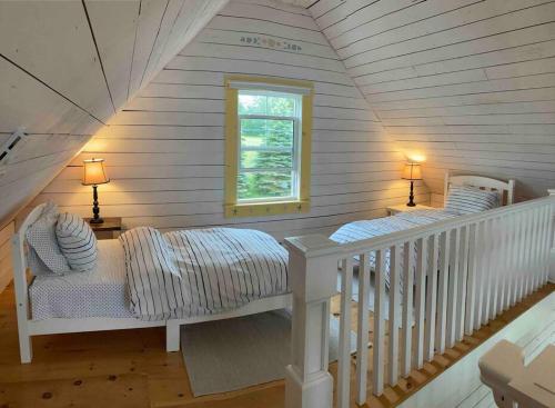 a attic room with two beds and a window at Sea Cliff Cottage in Edwardsville