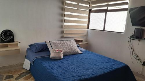 a bedroom with a blue bed with a pillow and a clock at Laureles 401 in Medellín