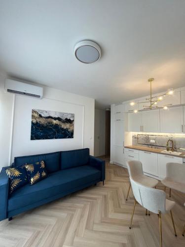 a living room with a blue couch and a kitchen at Apartament Vulcano Komfort Nowy Ursus in Warsaw
