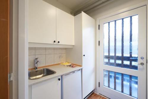 a kitchen with white cabinets and a sink and a window at Motel Apartments in Tønder