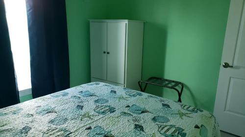 a green bedroom with a bed and a cabinet at Old Wooden Bridge Resort & Marina in Big Pine Key