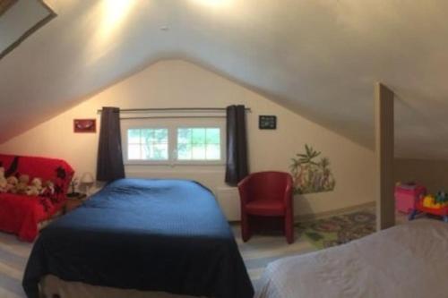 - une chambre avec un lit bleu et une chaise rouge dans l'établissement Maison Sainte Cécile proche plage et commerces, à Camiers