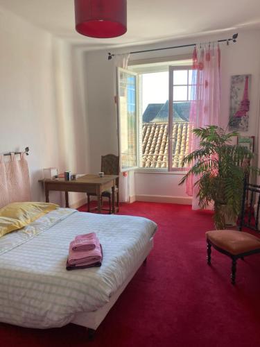 um quarto com uma cama, uma mesa e uma janela em Les chambres de Marielou em Aurillac