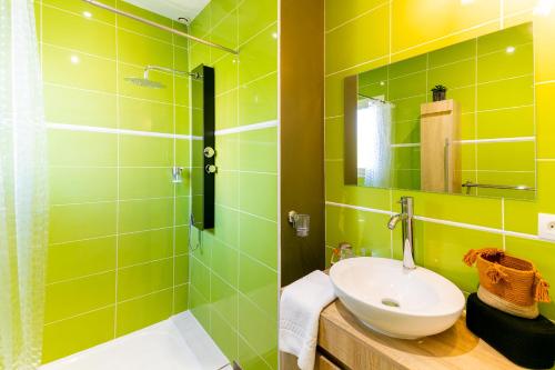 une salle de bain verte avec un lavabo et une douche dans l'établissement Villa Évasion Charme et Détente, à Maraussan