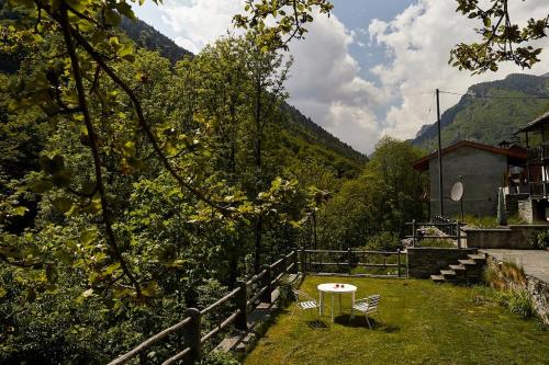 CranaにあるWild Valley Forest View 4 in Valle Onsernoneの柵付近の芝生のテーブルと椅子