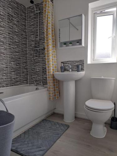 a bathroom with a sink and a toilet and a bath tub at Comfy home near airport in Speke