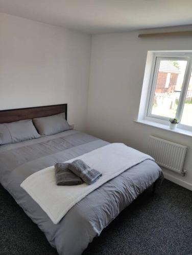 a bed in a white room with a window at Comfy home near airport in Speke