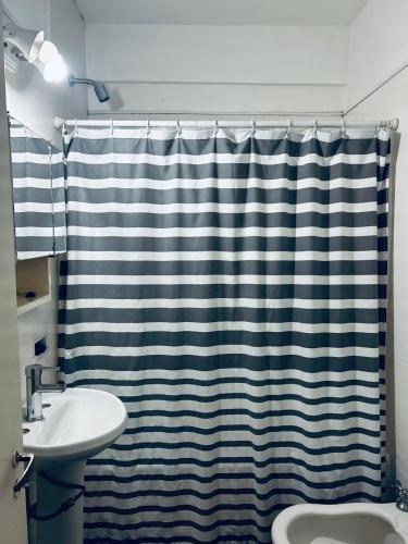 uma casa de banho com uma cortina de chuveiro e um lavatório em Departamento Moya 25 em Bragado