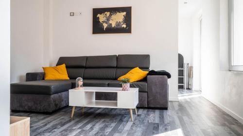 a living room with a black couch and yellow pillows at Le Modernisme - Joli T3 lumineux pour 4 pers in Poitiers