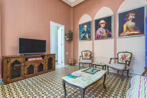 a living room with a tv and paintings on the walls at 961 Station Apartments in Mar Mikhael in Beirut