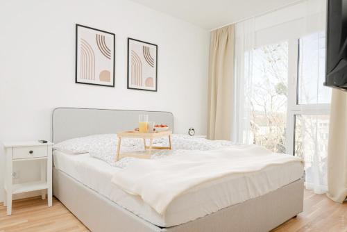 a white bedroom with a bed with a table on it at Oidahome - Apartment am Hauptbahnhof - contactless Self-Check-IN in Graz