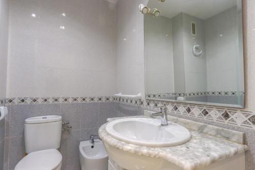 ein Badezimmer mit einem Waschbecken, einem WC und einem Spiegel in der Unterkunft 004 - Club Náutico 001 - comfortHOLIDAYS in Santa Pola