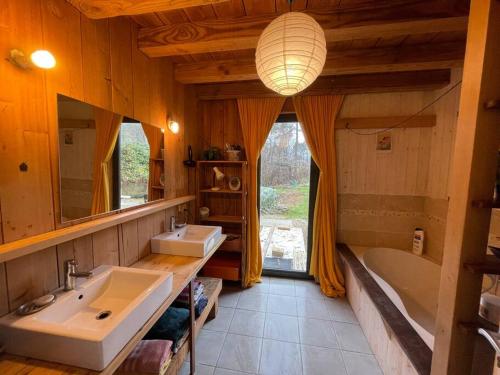 une salle de bain avec deux lavabos, une baignoire et un miroir dans l'établissement Maison Bois, à Sergeac