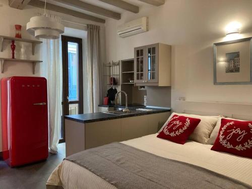 uma cozinha com uma cama e um frigorífico vermelho em Il Torchietto, incanto nel cuore di Milano em Milão