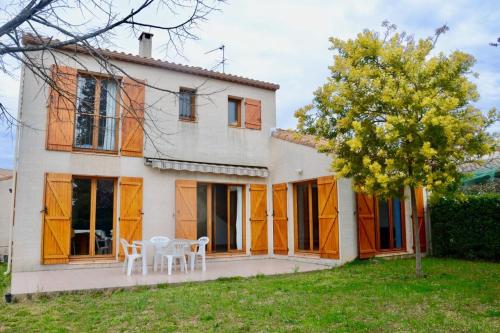 ein Haus mit zwei weißen Tischen und einem Baum in der Unterkunft The pleasant - 10 minutes from the center of Montpellier! in Montpellier