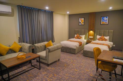ギルギットにあるDestination Hotel Gilgitのベッド2台とソファが備わるホテルルームです。