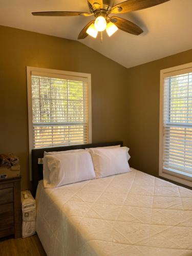 1 dormitorio con 1 cama, ventilador de techo y 2 ventanas en Louisiana State Cabin en West Point