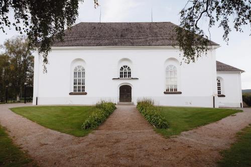 a white church with a pathway in front of it at STF Undersvik Gårdshotell & Vandrarhem in Vallsta