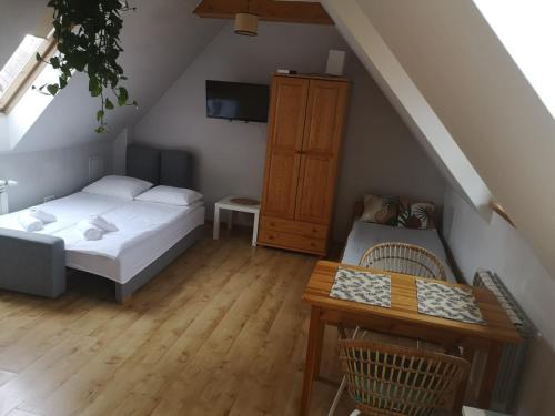 een slaapkamer op zolder met 2 bedden en een tafel bij Apartament Stary Rynek in Stary Sącz