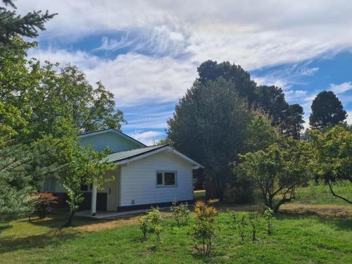 a small white house in a field with trees at Linaje Hotel Boutique & Relax in Lago Puelo