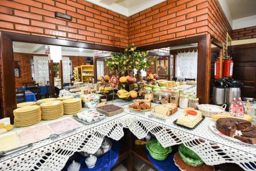 un buffet con pasteles y otros alimentos en una mesa en Hotel Pequenino, en Canela