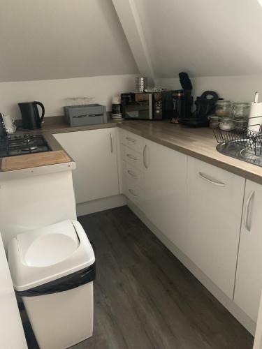 a kitchen with white cabinets and a counter top at Lovely one bedroom apartment in Llandudno