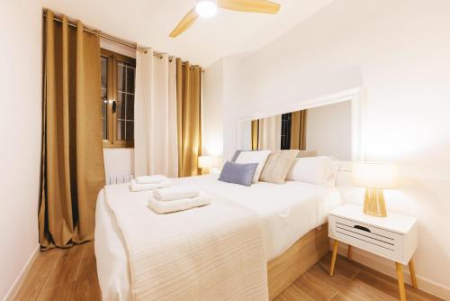 a white bedroom with a bed and a table with a lamp at Bravissimo Auriga, Old town retreat in Girona
