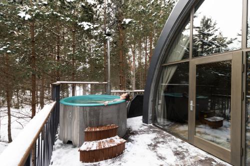 a house with a hot tub on a deck in the snow at Jungle SPA bungalows in Žocenes Ciems