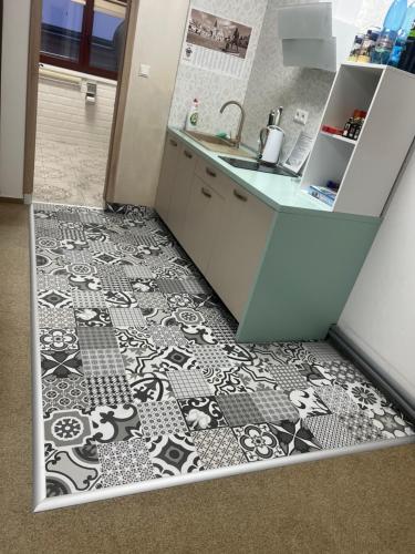 a kitchen with a black and white tile floor at Centrum Apartmán Armida in Bardejov