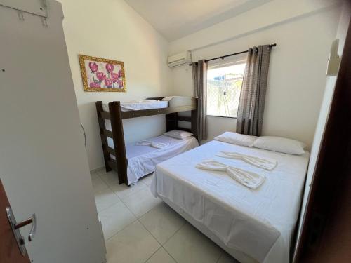 two beds in a small room with a window at Coroa Aconchego in Porto Seguro