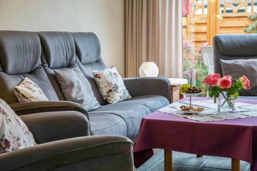 ein Wohnzimmer mit einem Sofa und einem Tisch mit Blumen in der Unterkunft Ferienhaus an der Baeke B in Bad Zwischenahn