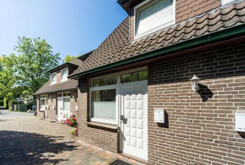 uma casa de tijolos com portas brancas numa rua em Ferienhaus an der Baeke E em Bad Zwischenahn