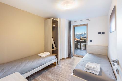 Habitación pequeña con 2 camas y balcón. en La Sorgente Ville di Fiemme, en Carano
