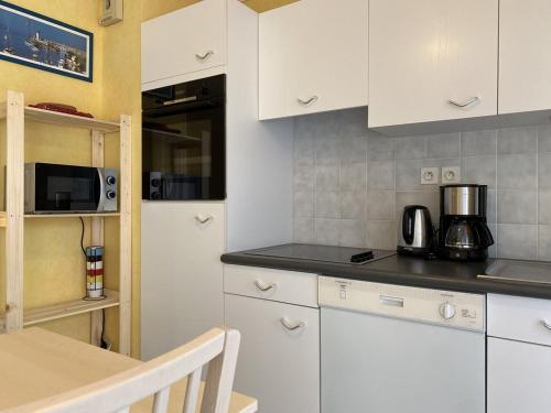 une cuisine avec des armoires blanches, une table et un micro-ondes dans l'établissement 533 - Appartement T1 situé à quelques pas de la grande plage d'Erquy et du centre, à Erquy