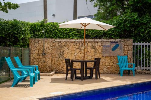 una mesa con sillas y una sombrilla junto a la piscina en HOTEL OCEANIA en Cartagena de Indias