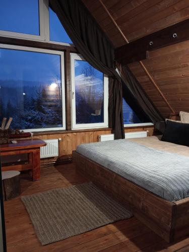 a bedroom with a bed and a table and windows at Ранчо в Карпатах in Bukovel