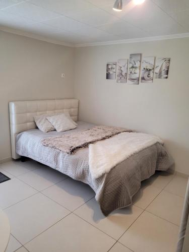 - un lit dans une chambre blanche avec 2 photos sur le mur dans l'établissement Studio Corbas, à Corbas