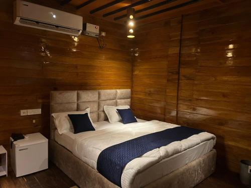 1 dormitorio con 1 cama grande y paredes de madera en Lemonwood cottage, en North Lakhimpur