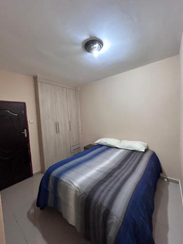 a bedroom with a bed with a blue blanket at Tranquil Room in Apartment in Lusaka